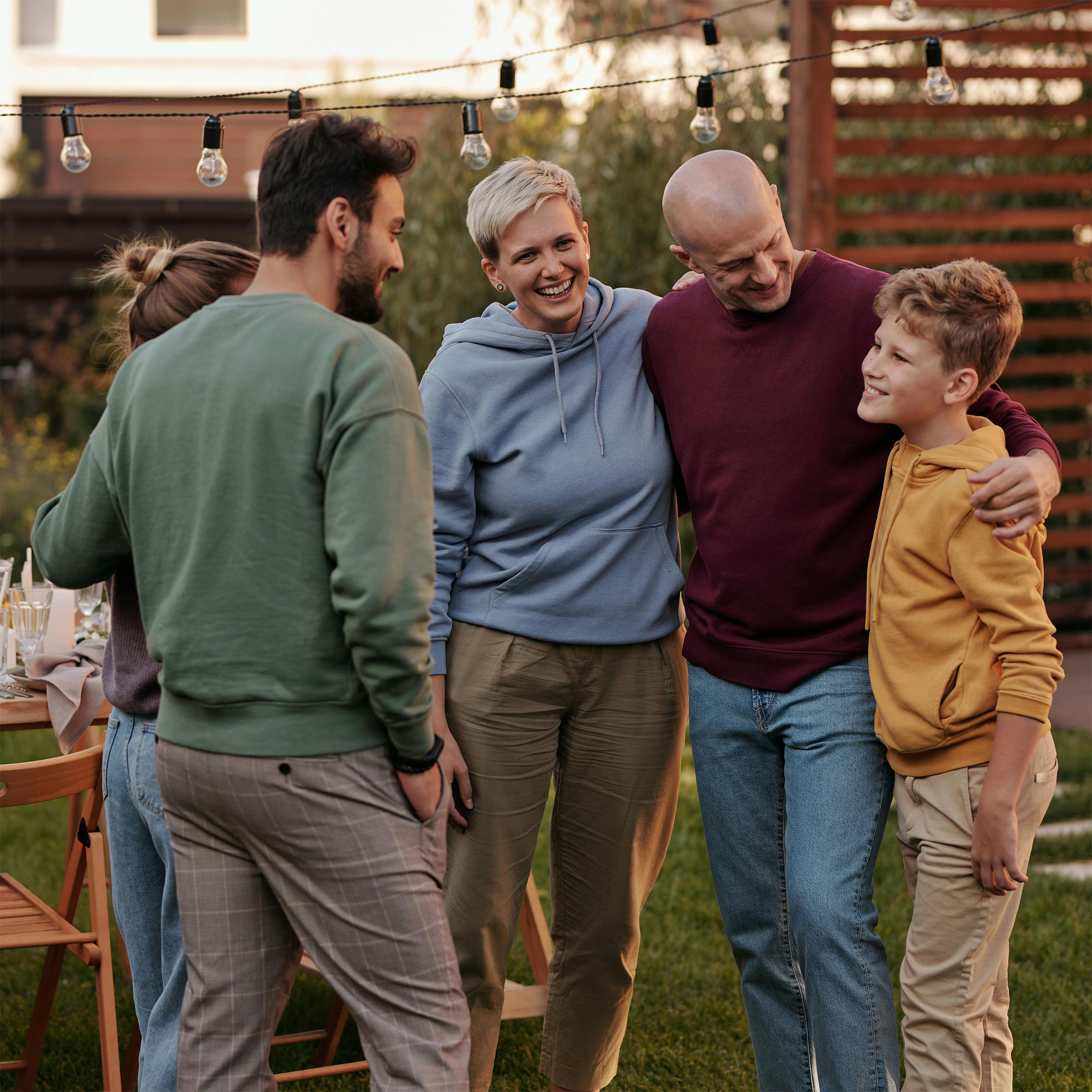 Two couples and a young boy standing outside at dusk smiling 